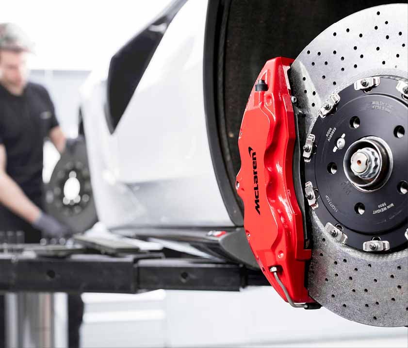 Red McLaren brake caliper with rotors exposed with wheel off to be serviced and changed