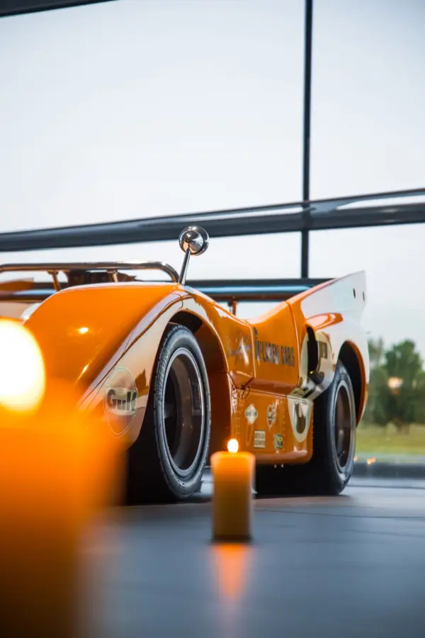 A lit candle beside the papaya McLaren M8D Can-Am car